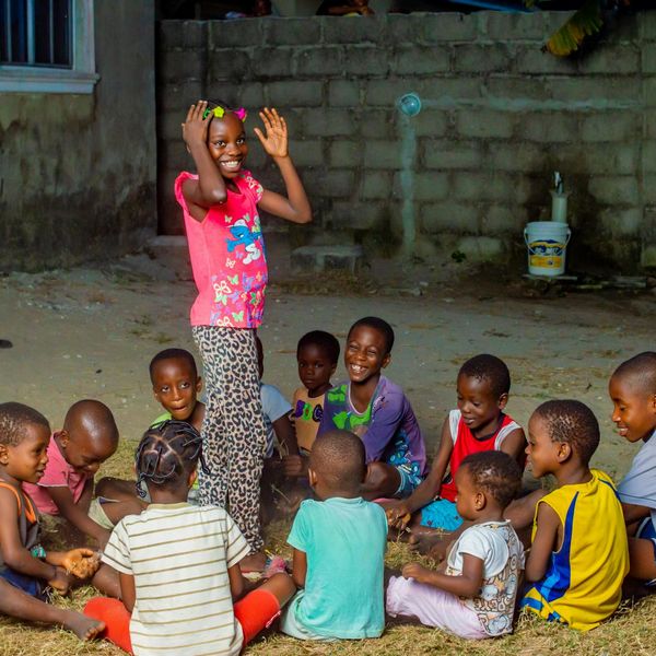 A group of diverse children sitting in a circle and smiling.