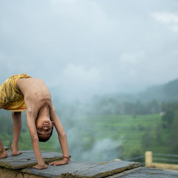 Child in a calm tree yoga pose against a serene background.